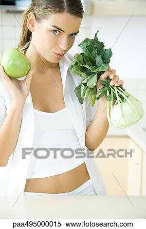 Woman holding up fresh kohlrabi and apple, looking at camera View Large Photo Image Stock Photography - Woman holding up fresh kohlrabi and apple, looking at camera. Fotosearch