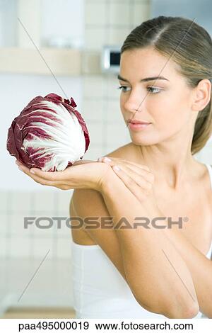 Woman looking at and holding a head of radicchio lettuce View Large Photo Image Stock Photo - Woman looking at and holding a head of radicchio lettuce. Fotosearch