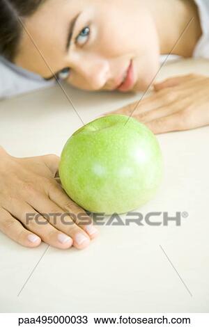 Woman resting head on counter behind apple, looking up, focus on foreground View Large Photo Image Stock Image - Woman resting head on counter behind apple, looking up, focus on foreground. Fotosearch