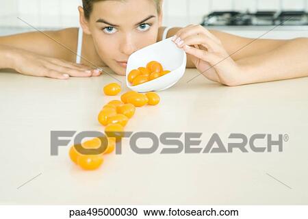 Woman spilling yellow cherry tomatoes out of a small dish, looking at camera View Large Photo Image Stock Image - Woman spilling yellow cherry tomatoes out of a small dish, looking at camera. Fotosearch