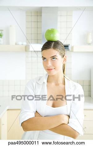 Young woman balancing an apple on her head, looking up View Large Photo Image Stock Image - Young woman balancing an apple on her head, looking up. Fotosearch