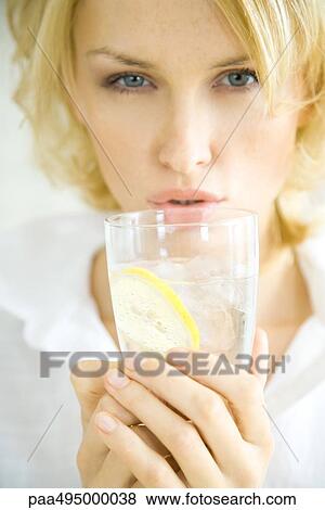 Young woman holding up a glass of water, puckering lips, head and shoulders View Large Photo Image Stock Photo - Young woman holding up a glass of water, puckering lips, head and shoulders. Fotosearch