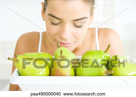 Young woman with eyes closed, smelling a bowl of pears View Large Photo Image Stock Image - Young woman with eyes closed, smelling a bowl of pears. Fotosearch
