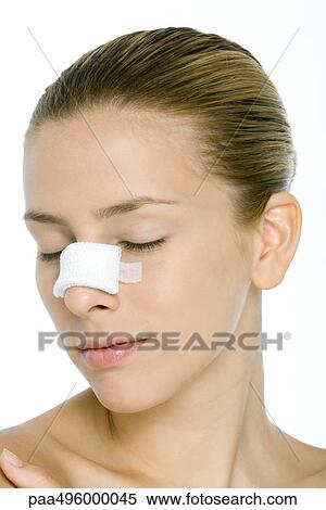 Stock Photography - Young woman with bandaged nose, eyes closed. Fotosearch