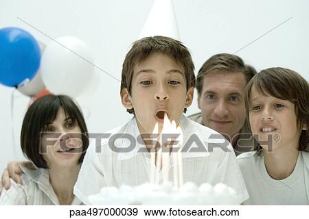 Boy about to blow out candles on birthday cake, family watching View Large Photo Image Stock Photo - Boy about to blow out candles on birthday cake, family watching. Fotosearch