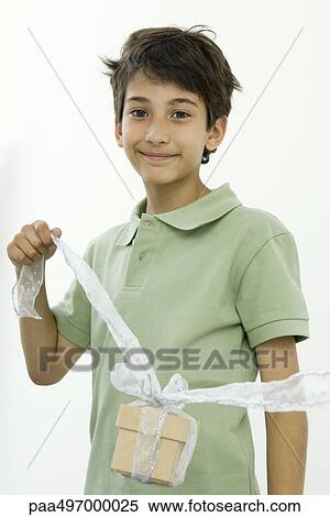 Boy holding present up by a ribbon, smiling at camera, portrait View Large Photo Image Stock Photography - Boy holding present up by a ribbon, smiling at camera, portrait. Fotosearch