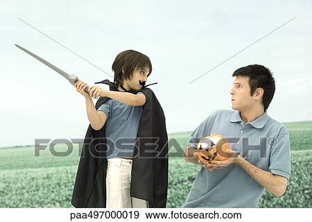 Father and son playing, man holding jack o' lantern, boy swinging sword View Large Photo Image Stock Photo - Father and son playing, man holding jack o' lantern, boy swinging sword. Fotosearch