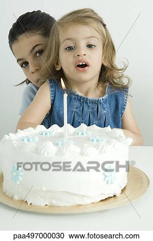Girl blowing out candle on birthday cake, sister peeking at camera from behind View Large Photo Image Stock Image - Girl blowing out candle on birthday cake, sister peeking at camera from behind. Fotosearch