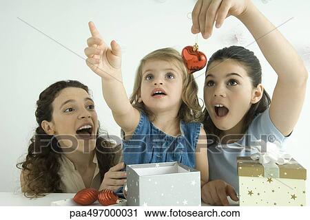 Girls opening presents, one holding ornament, other reaching up, mother watching View Large Photo Image Stock Image - Girls opening presents, one holding ornament, other reaching up, mother watching. Fotosearch