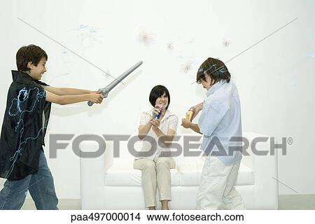Mother and two sons playing with spray string, one boy holding toy sword View Large Photo Image Picture - Mother and two sons playing with spray string, one boy holding toy sword. Fotosearch
