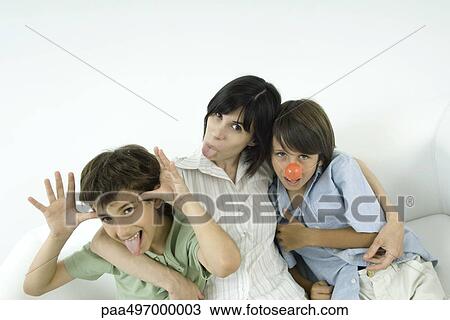 Stock Image - Mother and two sons, sticking out their tongues, one wearing clown's nose. Fotosearch