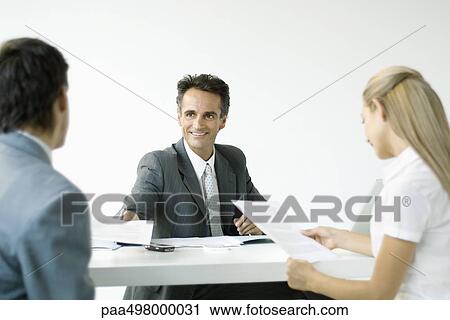 Businessman discussing contract with couple, smiling View Large Photo Image Stock Image - Businessman discussing contract with couple, smiling. Fotosearch