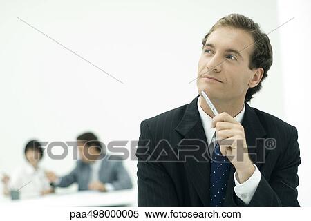 Businessman holding pen against chin, looking up in thought View Large Photo Image Stock Photography - Businessman holding pen against chin, looking up in thought. Fotosearch