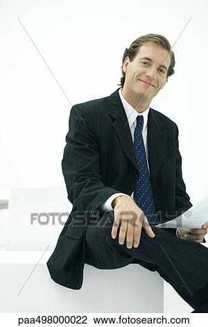 Businessman sitting, hand on knee, smiling at camera View Large Photo Image Stock Image - Businessman sitting, hand on knee, smiling at camera. Fotosearch