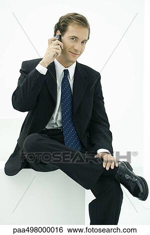 Businessman using cell phone, smiling at camera View Large Photo Image Stock Photograph - Businessman using cell phone, smiling at camera. Fotosearch