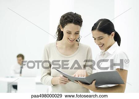 Female colleagues looking at document together, smiling View Large Photo Image Stock Photo - Female colleagues looking at document together, smiling. Fotosearch