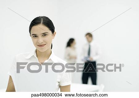 Female professional smiling at camera, colleagues in background View Large Photo Image Picture - Female professional smiling at camera, colleagues in background. Fotosearch