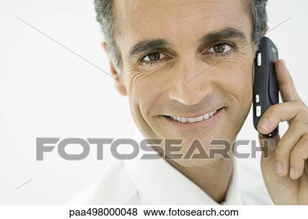 Man using cell phone, smiling at camera View Large Photo Image Stock Photo - Man using cell phone, smiling at camera. Fotosearch