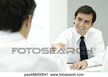 Two businessmen shaking hands, over the shoulder view View Large Photo Image Stock Photo - Two businessmen shaking hands, over the shoulder view. Fotosearch