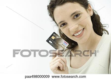 Stock Photo - Woman holding credit card, smiling at camera. Fotosearch