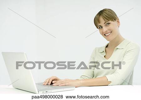 Woman using laptop computer, smiling at camera View Large Photo Image Stock Photo - Woman using laptop computer, smiling at camera. Fotosearch
