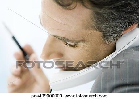 Man holding phone between chin and shoulder, side view, close-up View Large Photo Image Stock Photo - Man holding phone between chin and shoulder, side view, close-up. Fotosearch