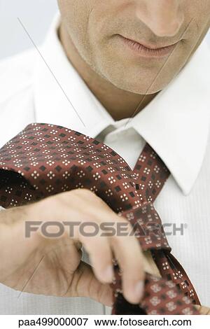 Stock Photo - Man putting on neck tie, close-up, cropped. Fotosearch