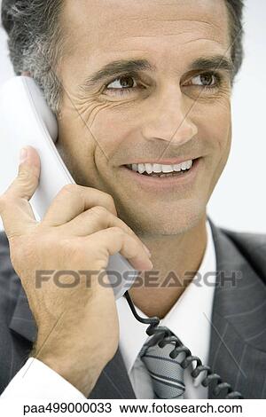 Man using landline phone, smiling, looking away View Large Photo Image Stock Image - Man using landline phone, smiling, looking away. Fotosearch