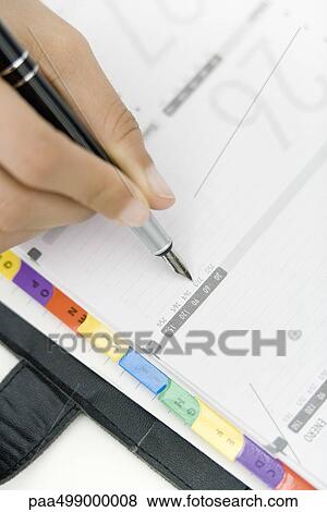 Stock Photo - Person writing in agenda, cropped view of hand. Fotosearch