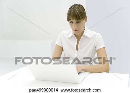 Picture - Woman using laptop computer, furrowing brow. Fotosearch