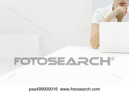 Woman using laptop computer, hand under chin, cropped view View Large Photo Image Stock Photograph - Woman using laptop computer, hand under chin, cropped view. Fotosearch