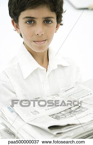 Stock Photo - Boy carrying stack of newspapers, smiling at camera. Fotosearch
