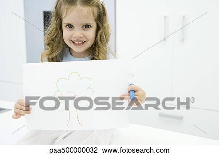 Little girl holding drawing of tree, smiling at camera View Large Photo Image Stock Image - Little girl holding drawing of tree, smiling at camera. Fotosearch