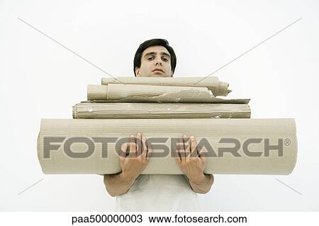 Stock Image - Man carrying large stack of corrugated cardboard, looking at camera. Fotosearch