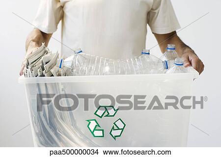 Man carrying recycling bin filled with plastic bottles and newspaper, cropped View Large Photo Image Picture - Man carrying recycling bin filled with plastic bottles and newspaper, cropped. Fotosearch