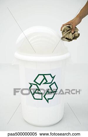 Stock Photography - Man's hand placing cardboard in recycling bin, cropped. Fotosearch