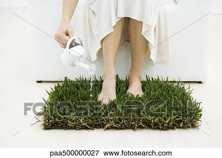 Woman watering small patch of grass with watering can, cropped view View Large Photo Image Stock Photo - Woman watering small patch of grass with watering can, cropped view. Fotosearch