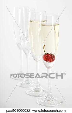 Champagne flutes, two filled with champagne, one with a cherry floating in it View Large Photo Image Stock Image - Champagne flutes, two filled with champagne, one with a cherry floating in it. Fotosearch
