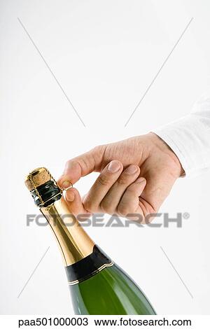 Stock Image - Hand opening champagne bottle. Fotosearch