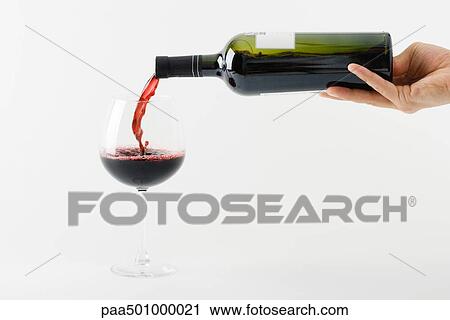 Stock Image - Hand pouring red wine into glass. Fotosearch