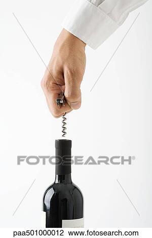 Stock Image - Hand uncorking wine bottle, cropped. Fotosearch