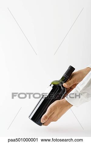 Stock Image - Man showing wine bottle, cropped view of hands. Fotosearch