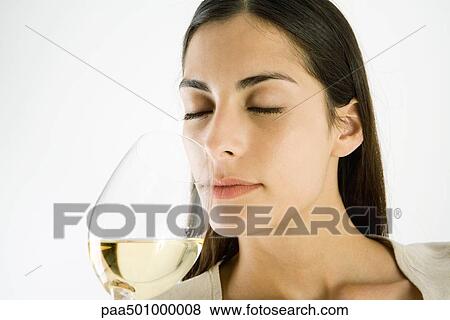 Stock Photo - Woman smelling glass of white wine, eyes closed. Fotosearch