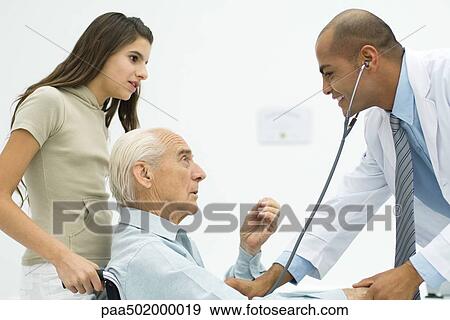 Stock Photo - Doctor listening to senior man's heart, teen girl watching. Fotosearch