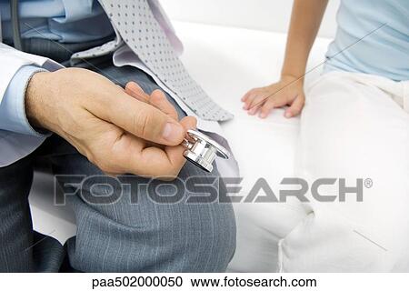 Stock Image - Doctor showing young patient stethoscope, cropped view. Fotosearch