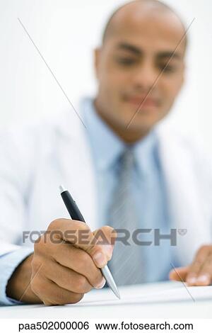 Stock Photograph - Doctor writing a prescription, focus on hand in the foreground. Fotosearch