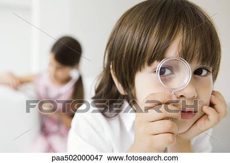 Stock Photo - Little boy looking through magnifying glass at camera. Fotosearch
