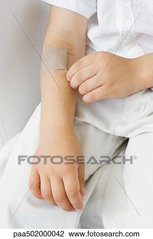 Little boy picking at adhesive bandage on his arm, cropped view View Large Photo Image Stock Image - Little boy picking at adhesive bandage on his arm, cropped view. Fotosearch