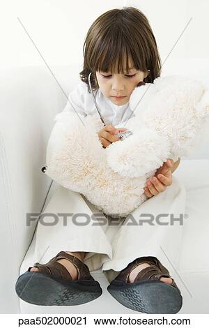 Stock Image - Little boy playing doctor with stuffed toy, using stethoscope. Fotosearch