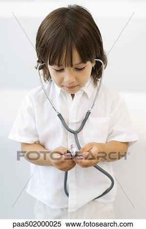 Stock Photography - Little boy playing with stethoscope, looking down. Fotosearch